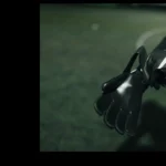 A person in a blue sports outfit is putting on black football goalkeeper gloves on a dimly lit soccer field. The ground, covered in artificial turf, features a white line in the background. Slightly cropped out of the frame, the scene almost feels like they’re preparing for more than just legal stuff. © Powerleague